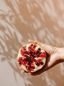 crop woman demonstrating ripe pomegranate